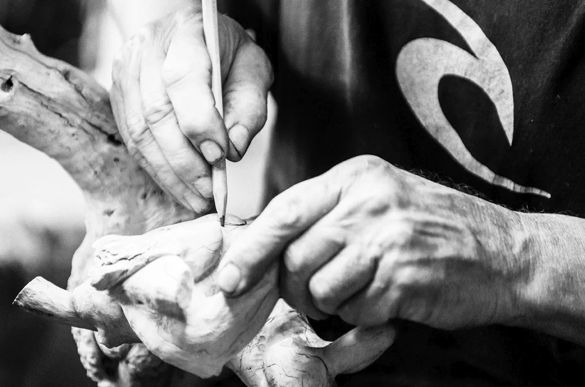 Les mains du sculpteur travaillant sur une sculpture en bois